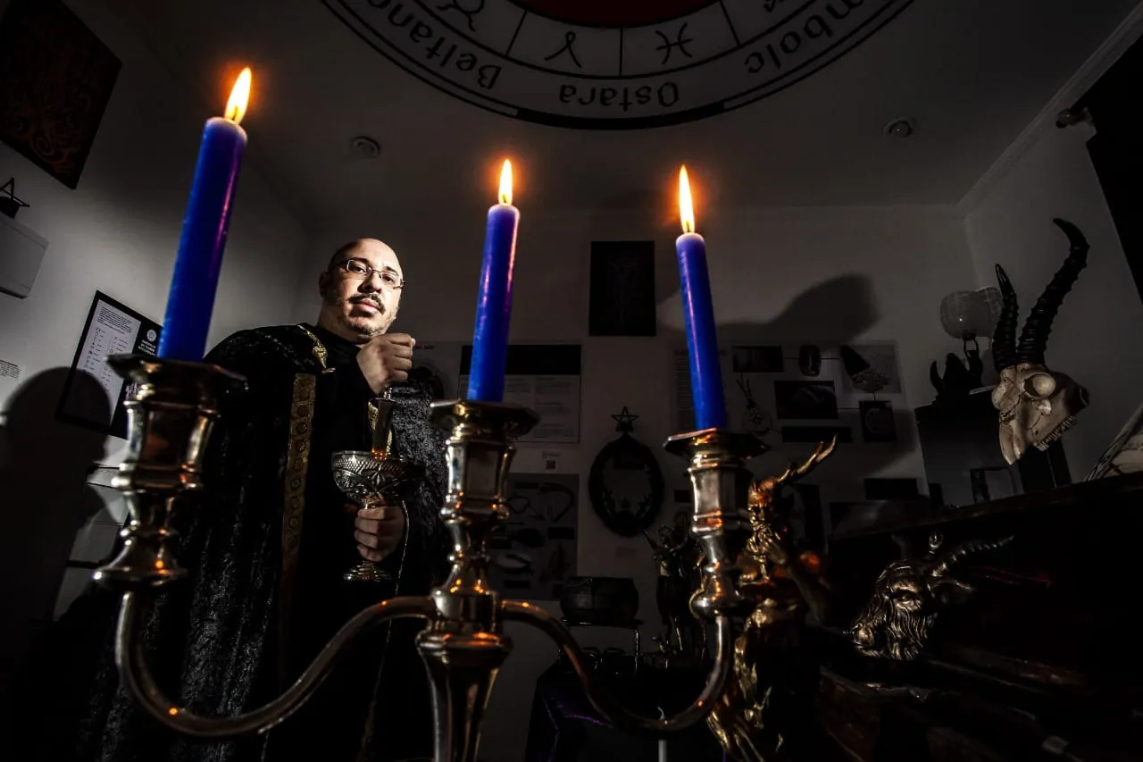 Claudiney Prieto escrevendo entre velas e livro aberto