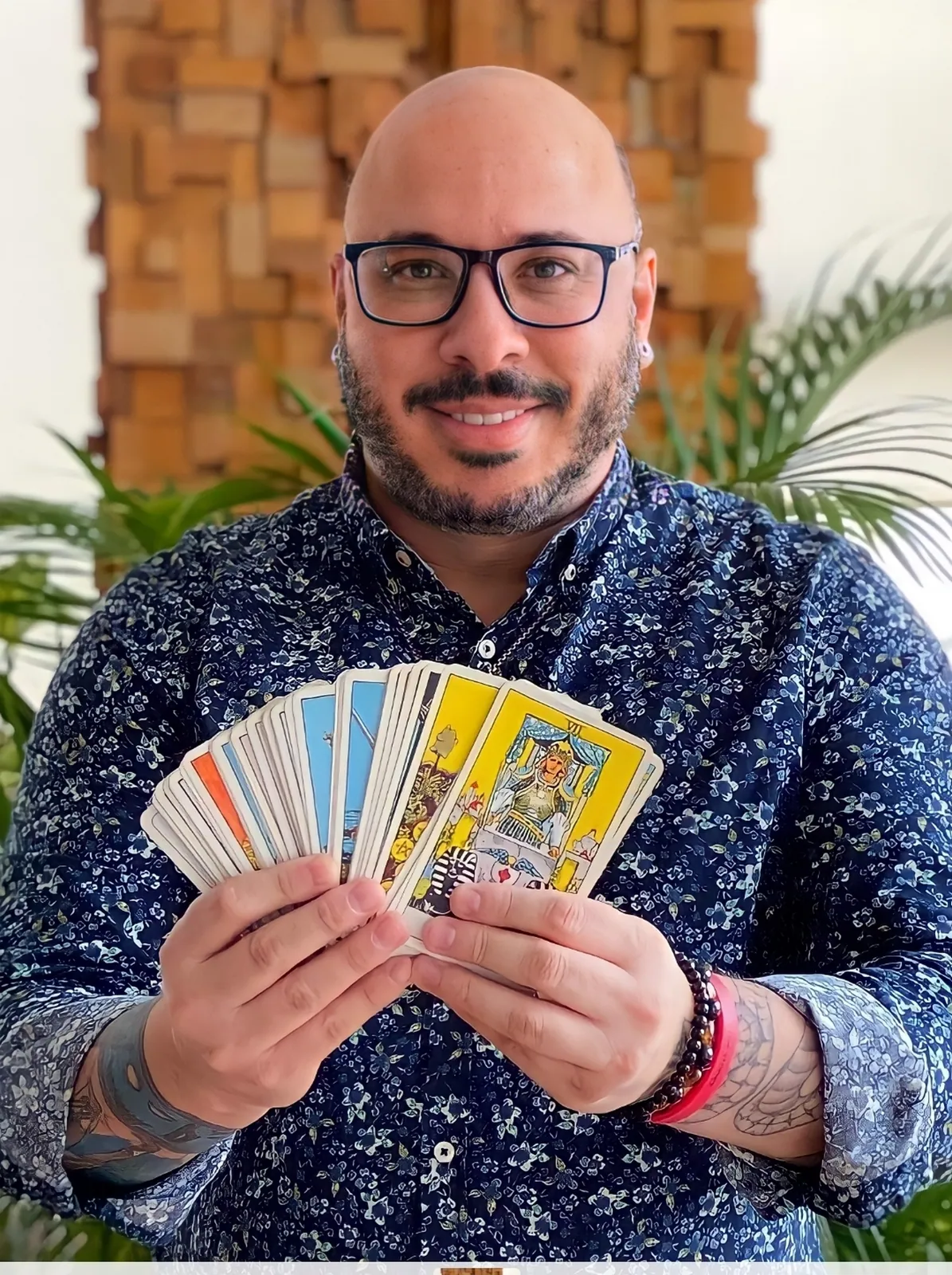 Claudiney Prieto sorrindo com cartas de Tarô abertas em leque